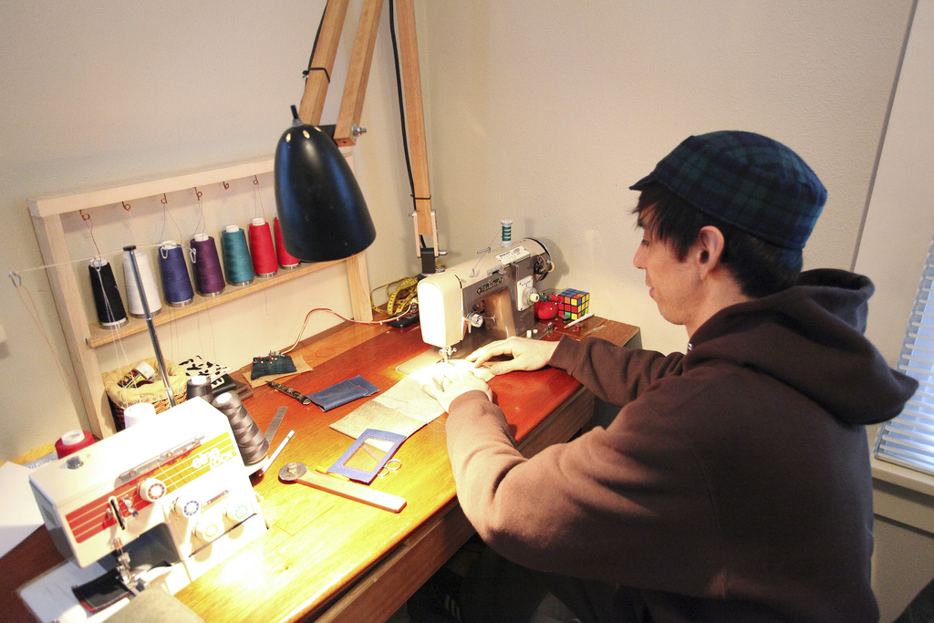 Santi sewing at an Elna overlock machine surrounded by thread spools