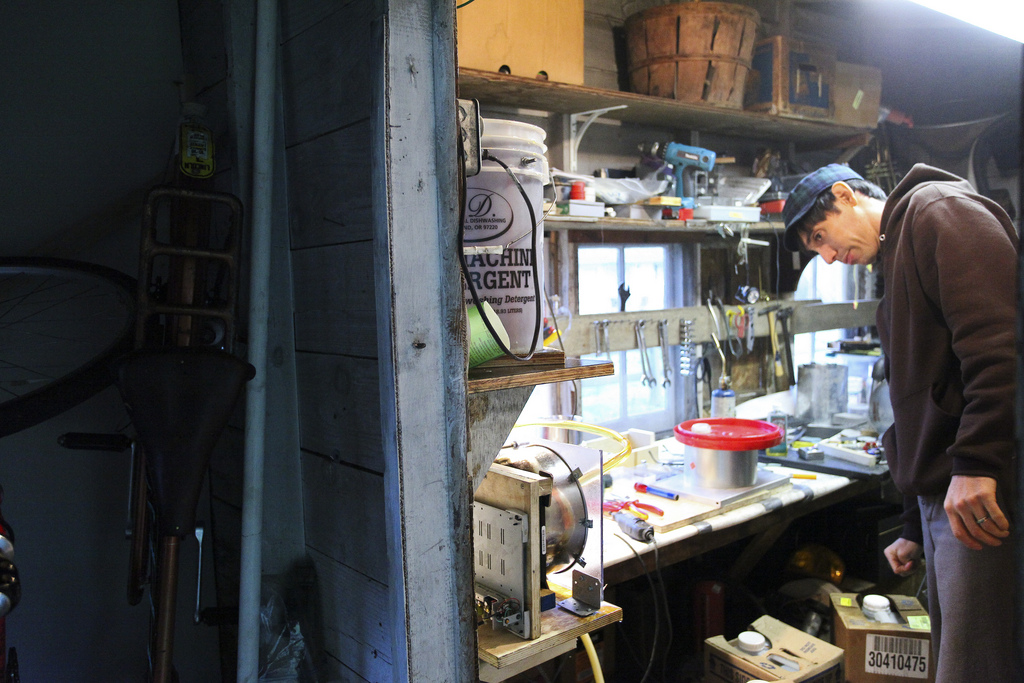 Santi leaning over his cluttered workbench in the workshop